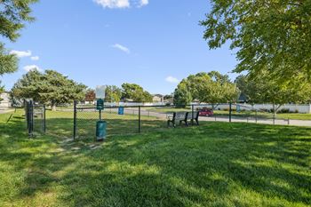 A park with a blue trash can and a picnic table.